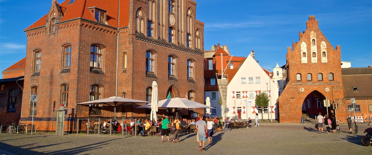 A historic square with a prominent red-brick building featuring arched windows and a tower.