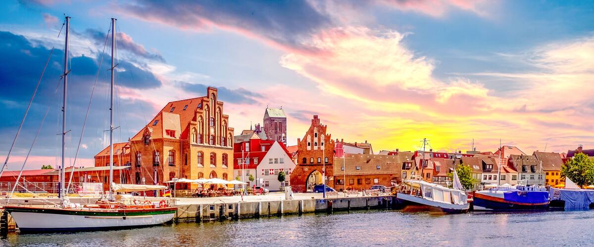A harbor with boats, a red brick building, and a sunset sky.
