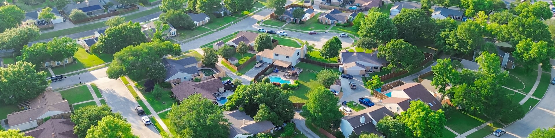 Panorama aerial view residential street in lush greenery neighborhood in Coppell Texas Dallas Fort Worth metroplex, row of detached single-family houses swimming pool, large backyard, grassy lawn