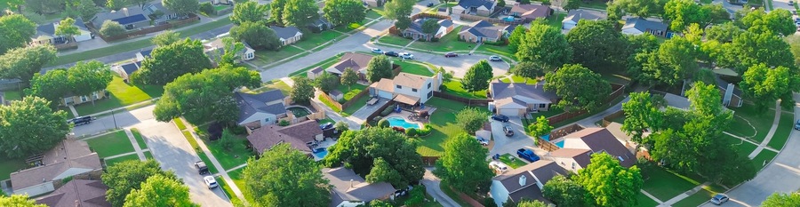 Panorama aerial view residential street in lush greenery neighborhood in Coppell Texas Dallas Fort Worth metroplex, row of detached single-family houses swimming pool, large backyard, grassy lawn