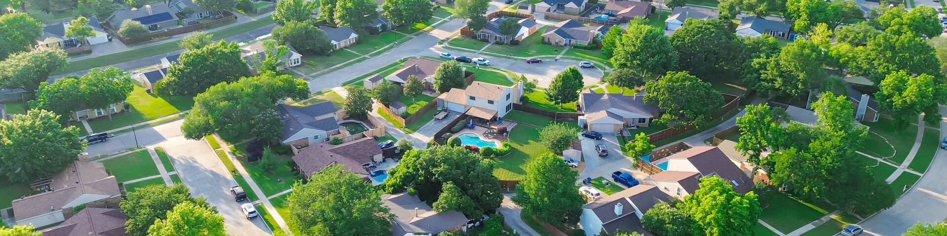 Panorama aerial view residential street in lush greenery neighborhood in Coppell Texas Dallas Fort Worth metroplex, row of detached single-family houses swimming pool, large backyard, grassy lawn