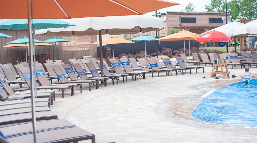 Upscale hotel swimming pool with row of pool lounge chairs reserved words wrap around, small plastic service flag with number in Grapevine, Texas, colorful beach umbrella, summer holiday event