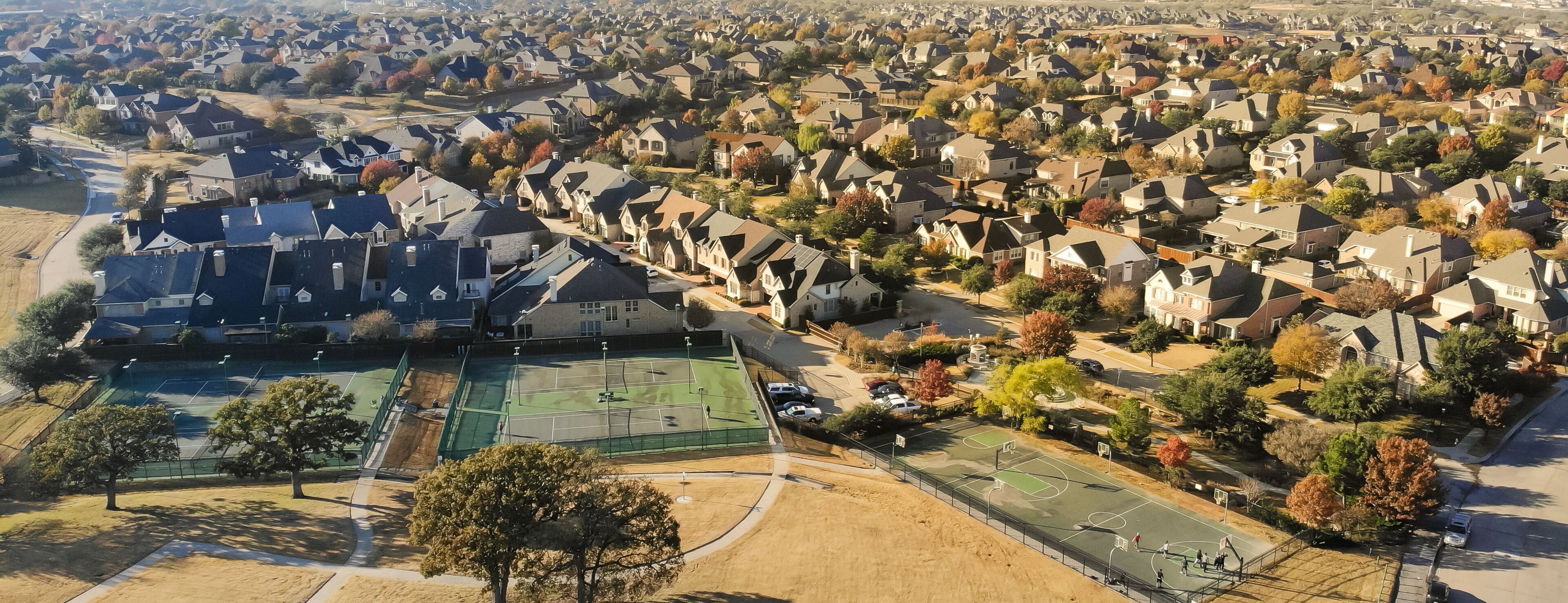 Panorama aerial view large grassy park square near tennis courts complex in residential neighborhood with colorful fall foliage near Dallas, Texas, America