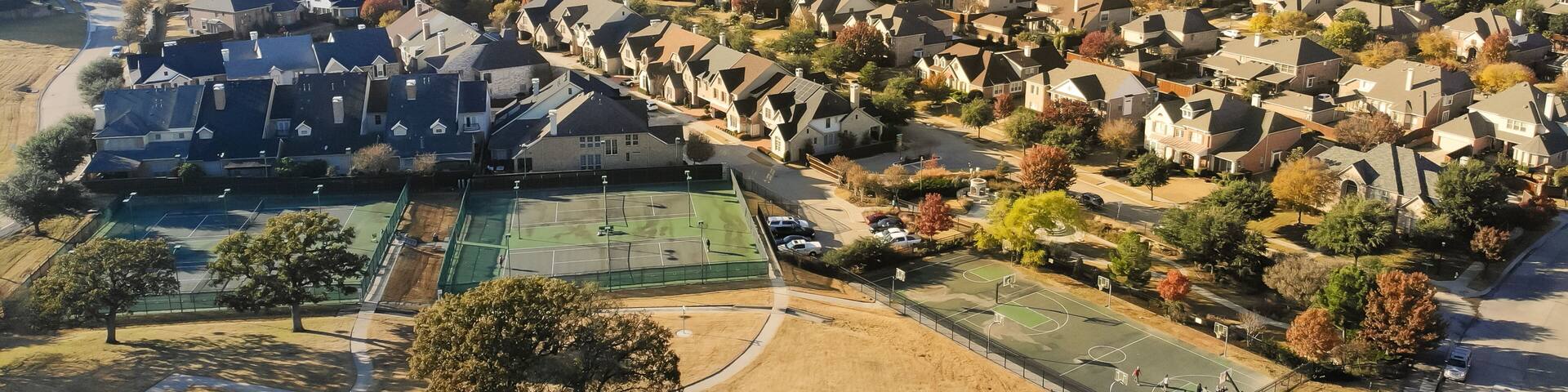 Panorama aerial view large grassy park square near tennis courts complex in residential neighborhood with colorful fall foliage near Dallas, Texas, America