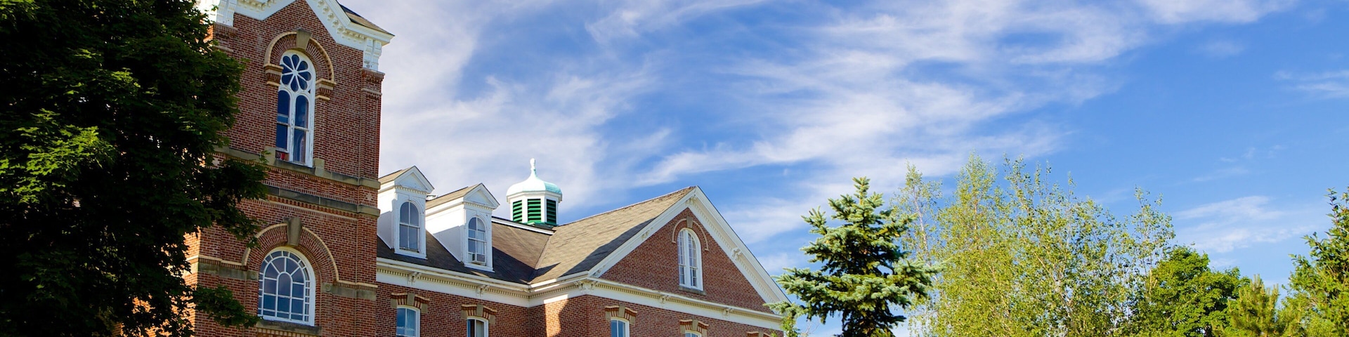 A large brick building with a green steeple and a clock tower.