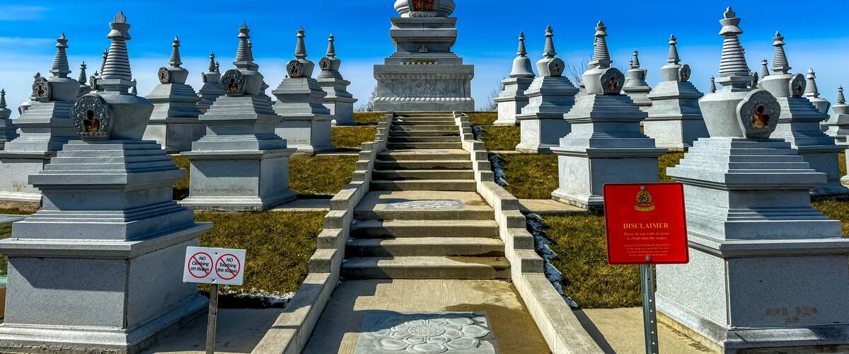 A series of white stupas with a central larger stupa, surrounded by a clear blue sky.