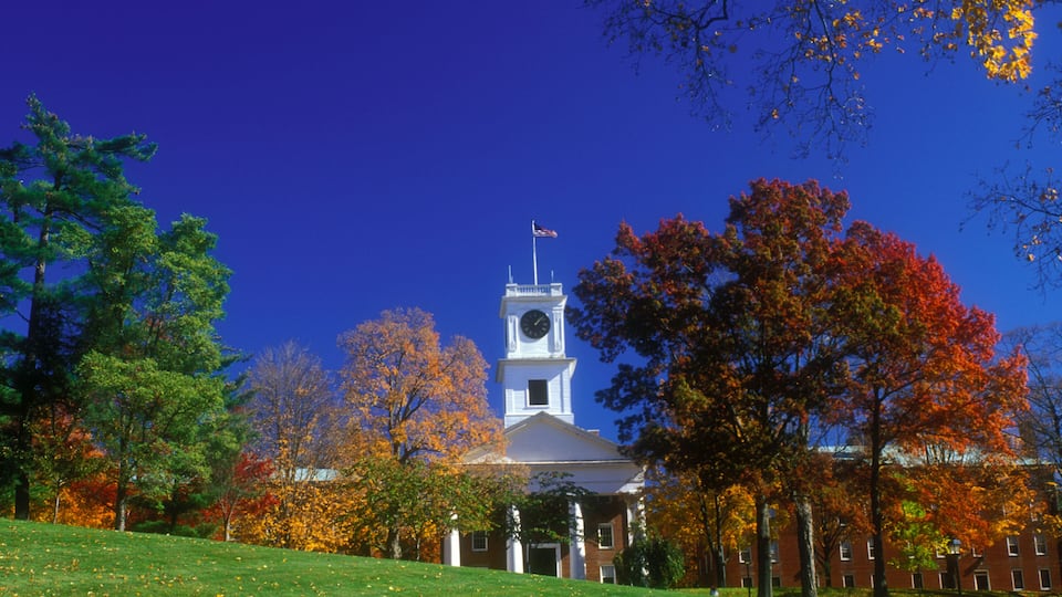 A building with a clock tower, surrounded by trees with autumn foliage.