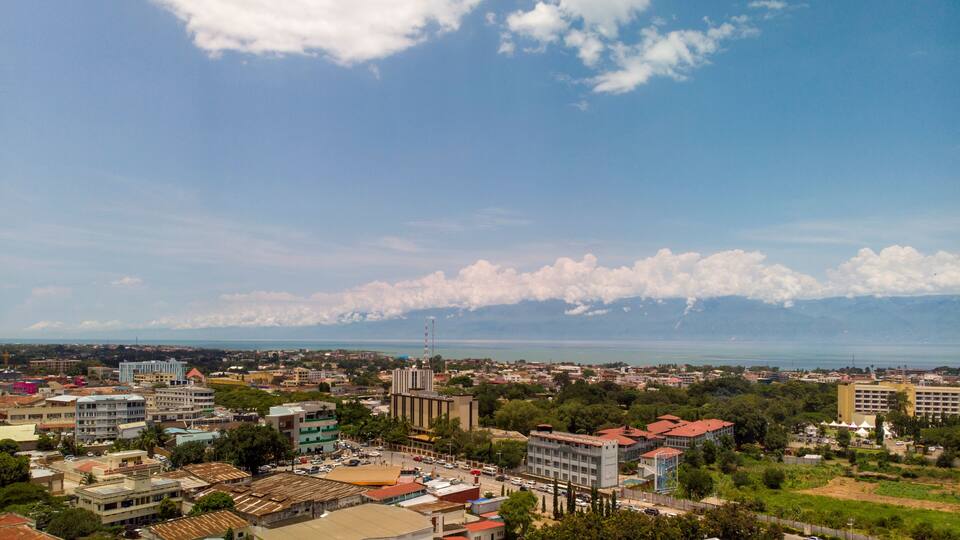 A cityscape with a mix of modern and traditional buildings, a clear sky, and distant mountains.