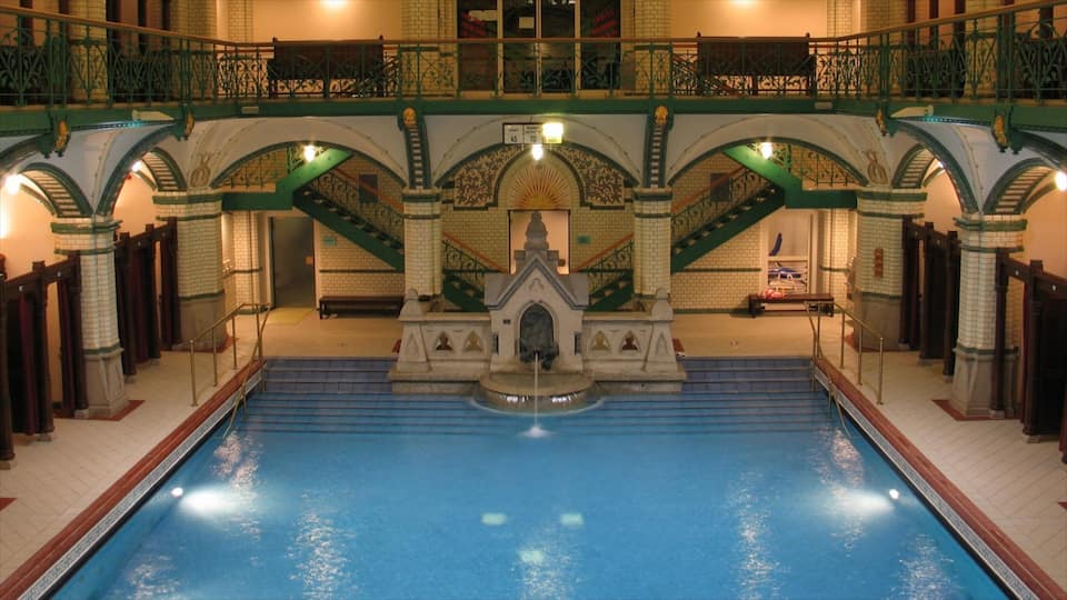 An indoor swimming pool with ornate arches and a statue in the center.