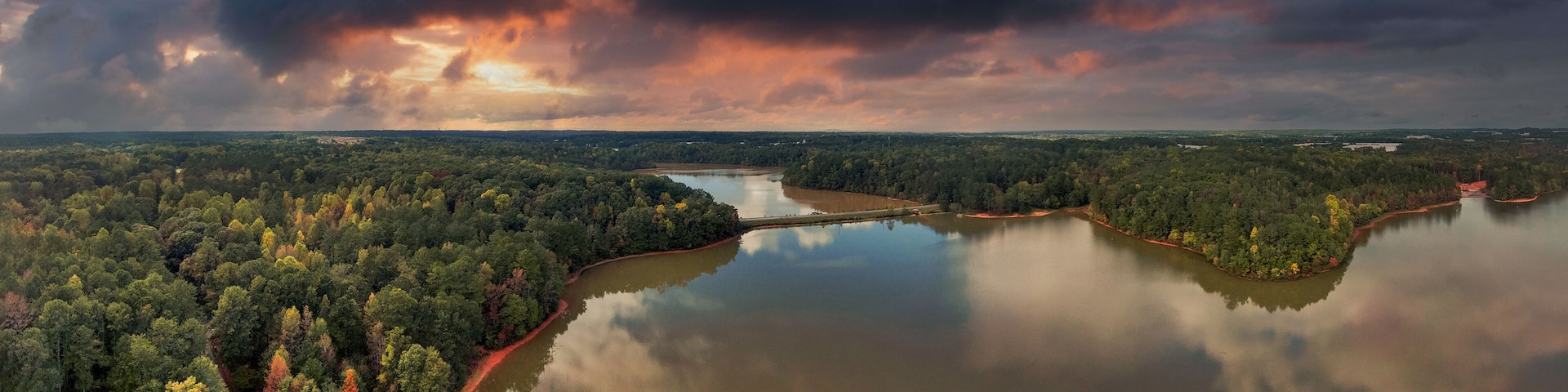 A river winding through a dense forest with a cloudy sky above.