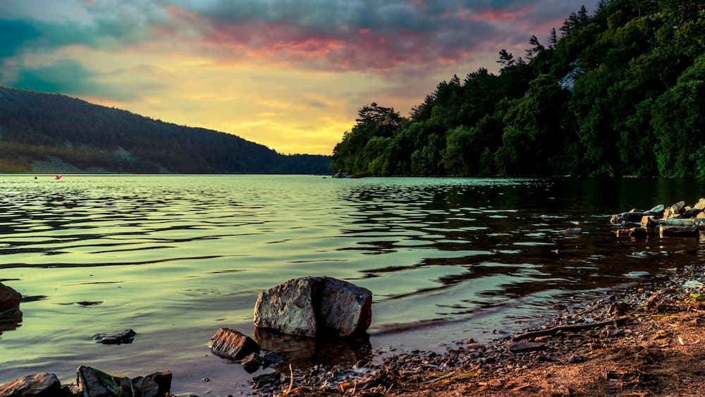 A small boulder protruding from the surface of the water as the sun sets over Devil's Lake in Baraboo, Wisconsin USA.