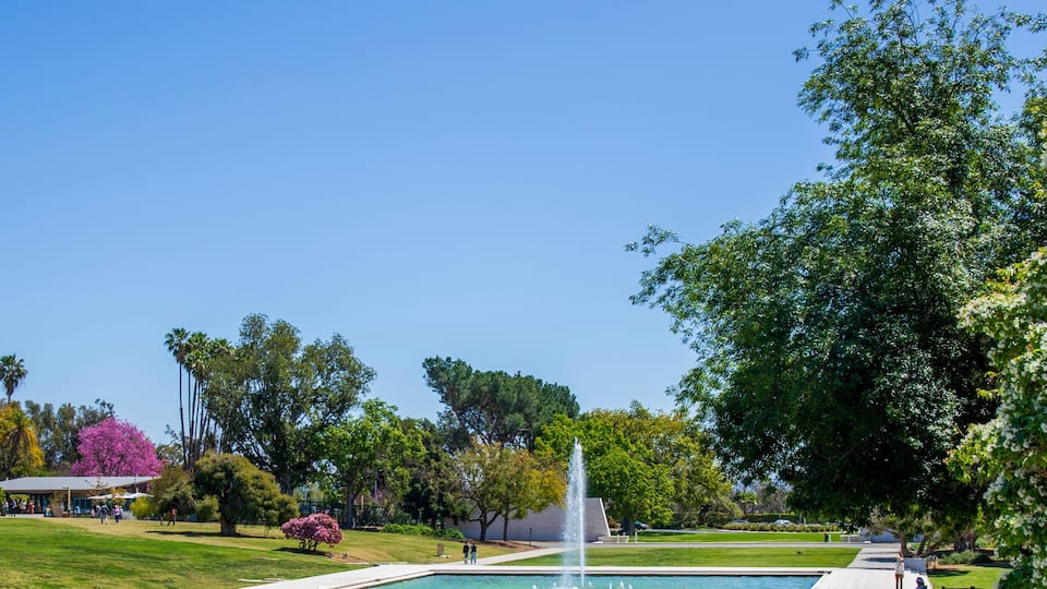 A park with a fountain, a pathway, and a grassy area.