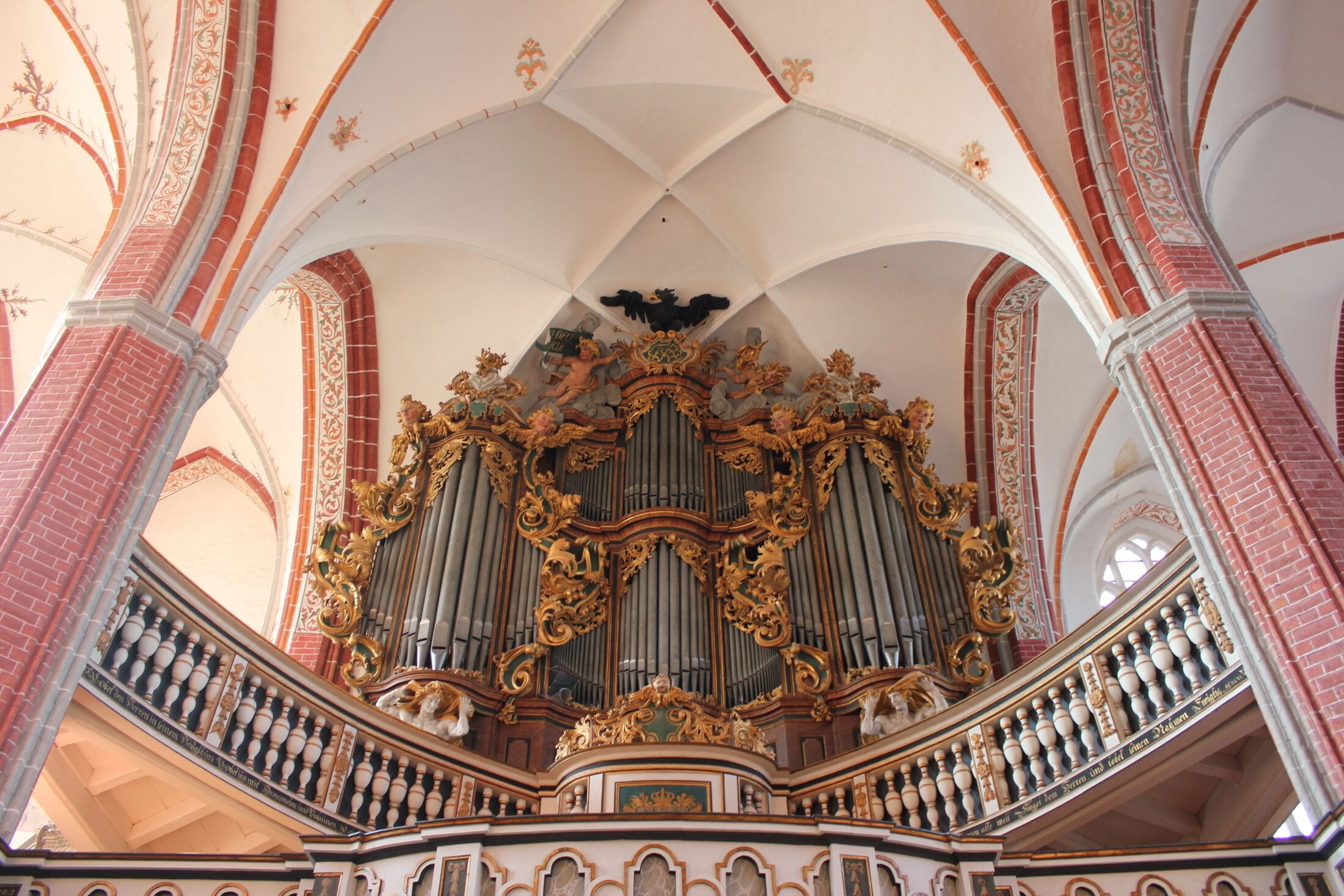 An ornate organ with intricate gold detailing and a balcony with balustrades.
