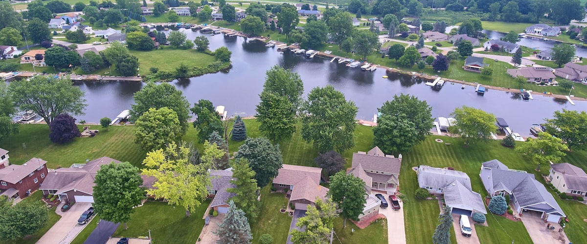 A lakeside residential area with houses, a dock, and a boat marina.