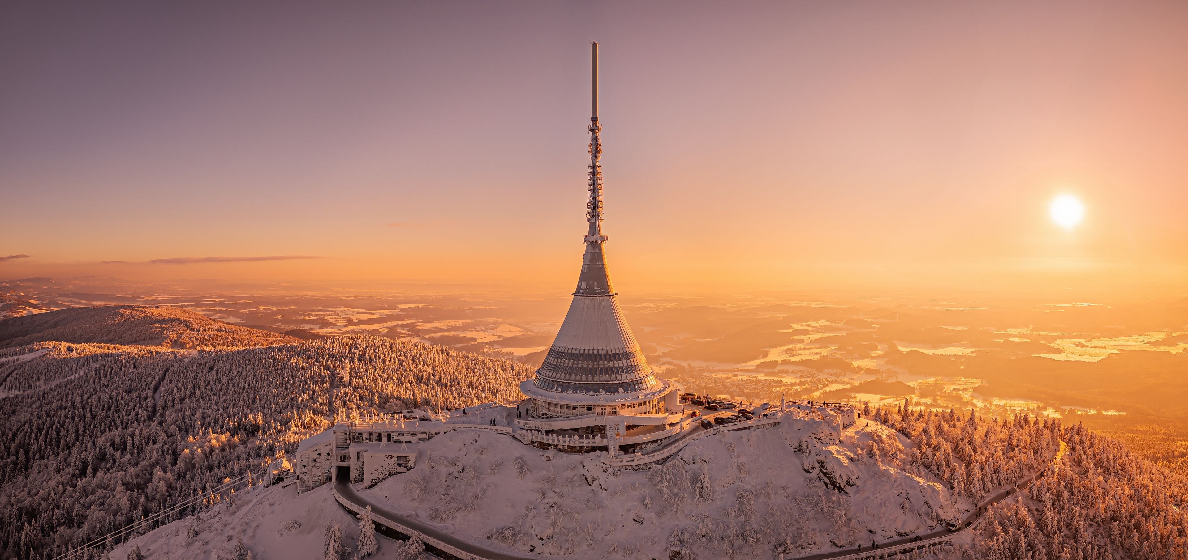Ein mit Schnee bedeckter Berg mit einem hohen Turm und einer kurvenreichen Straße.