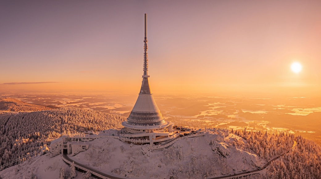 Ein mit Schnee bedeckter Berg mit einem hohen Turm und einer kurvenreichen Straße.