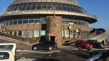 A large conical building with a stone base and a metal spire.