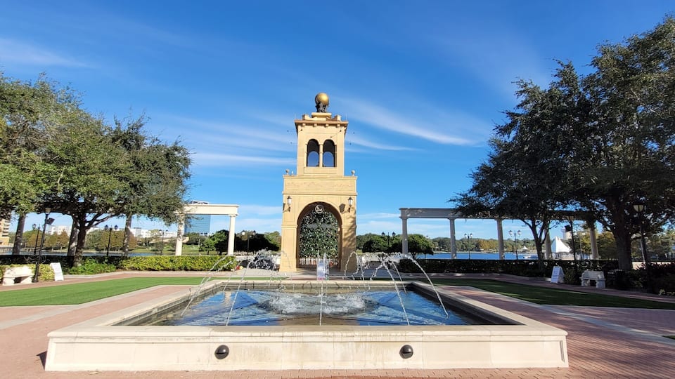 A fountain with water jets, a central tower with a dome, and surrounding greenery.