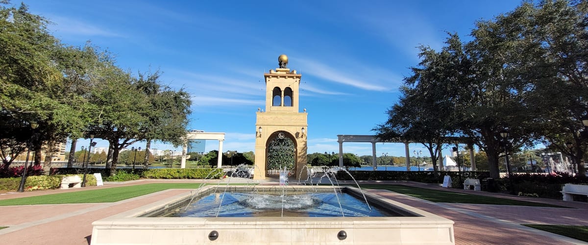 A fountain with water jets, a central tower with a dome, and surrounding greenery.