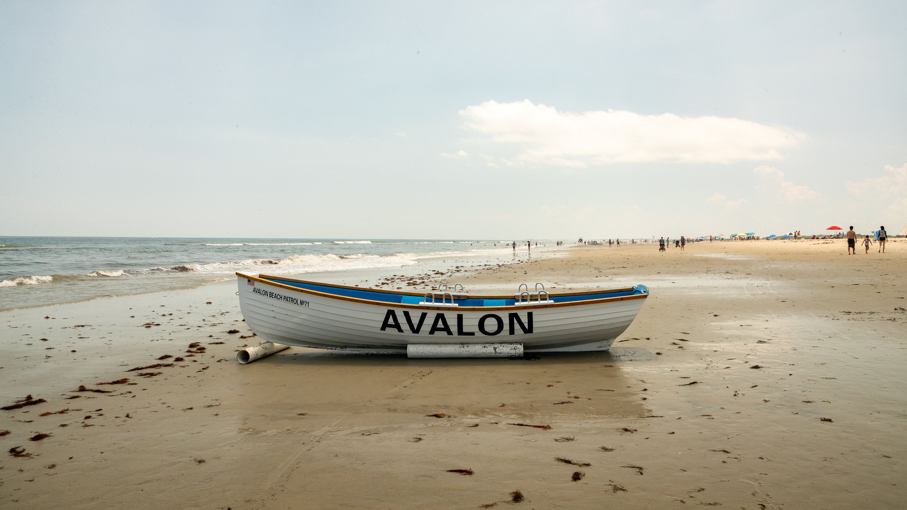 A boat named 'AVALON' on a sandy beach with the ocean in the background.