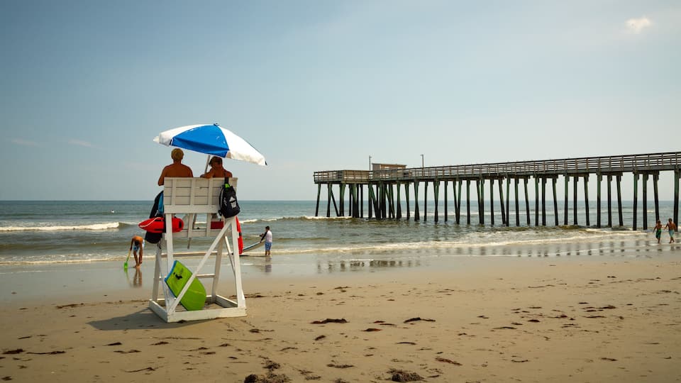 A beach with a lifeguard tower, a pier, and the ocean.