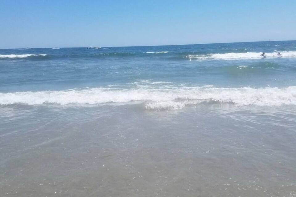 A beach with gentle waves and a clear blue sky.