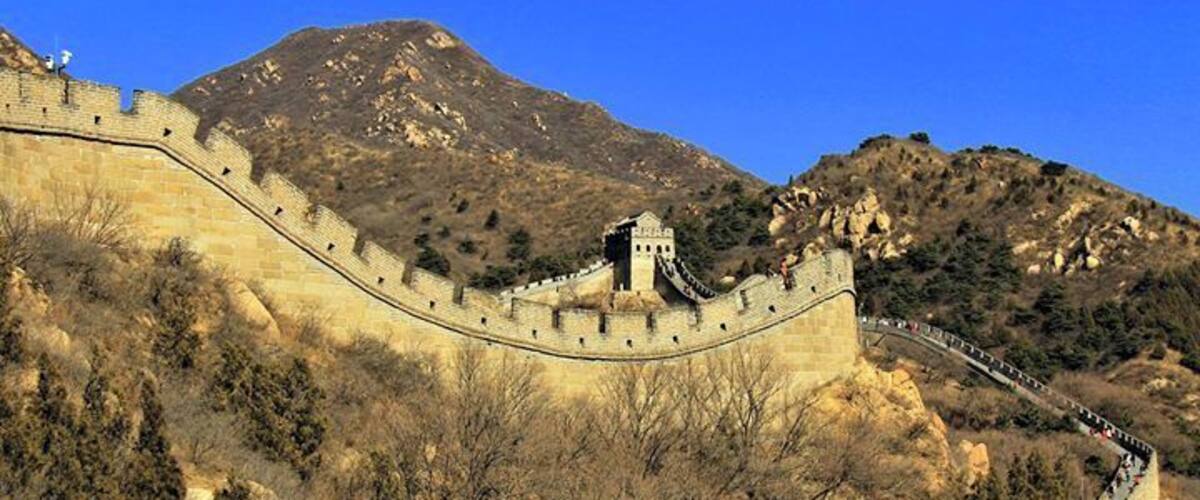 Die Chinesische Mauer schlängelt sich durch eine gebirgige Landschaft.