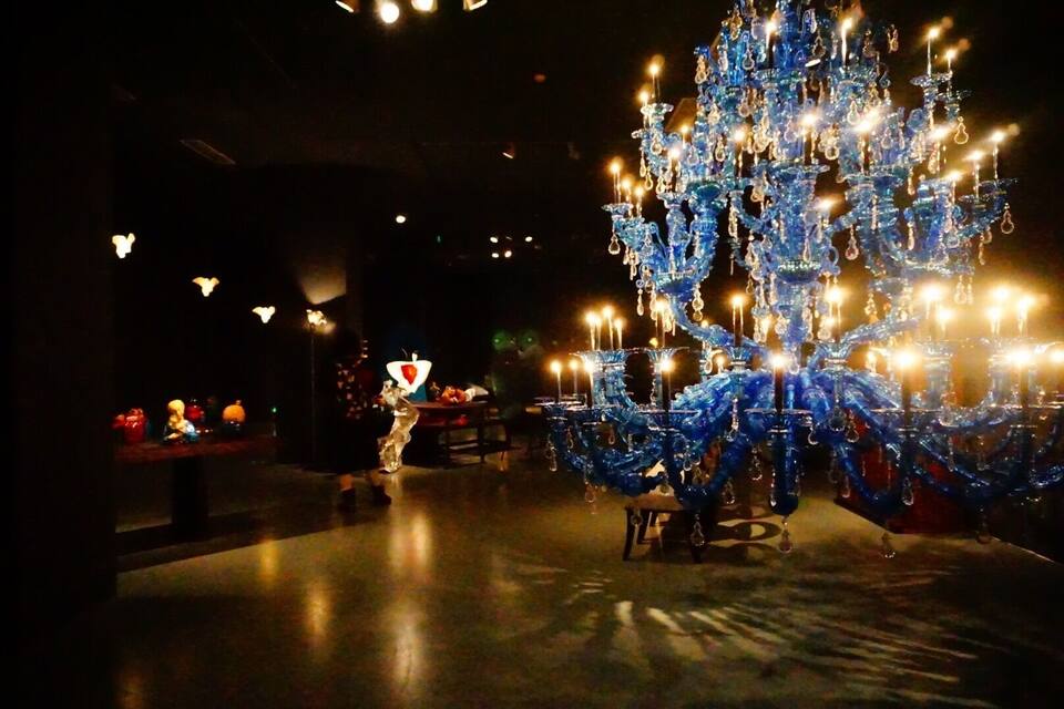 A large, ornate blue chandelier in a dimly lit room.