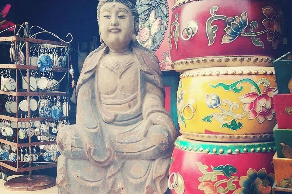 A Buddha statue, colorful containers, and a display of blue and white ceramic items.