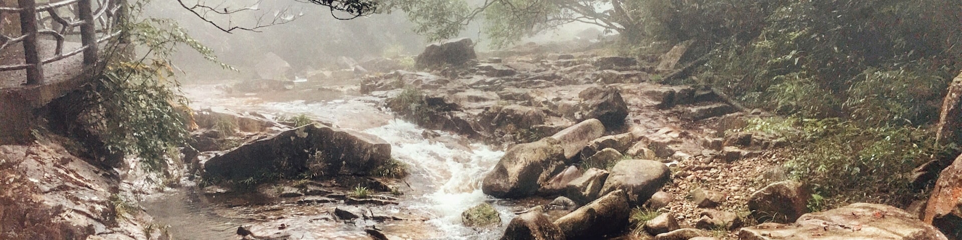 A rocky stream with a wooden bridge.