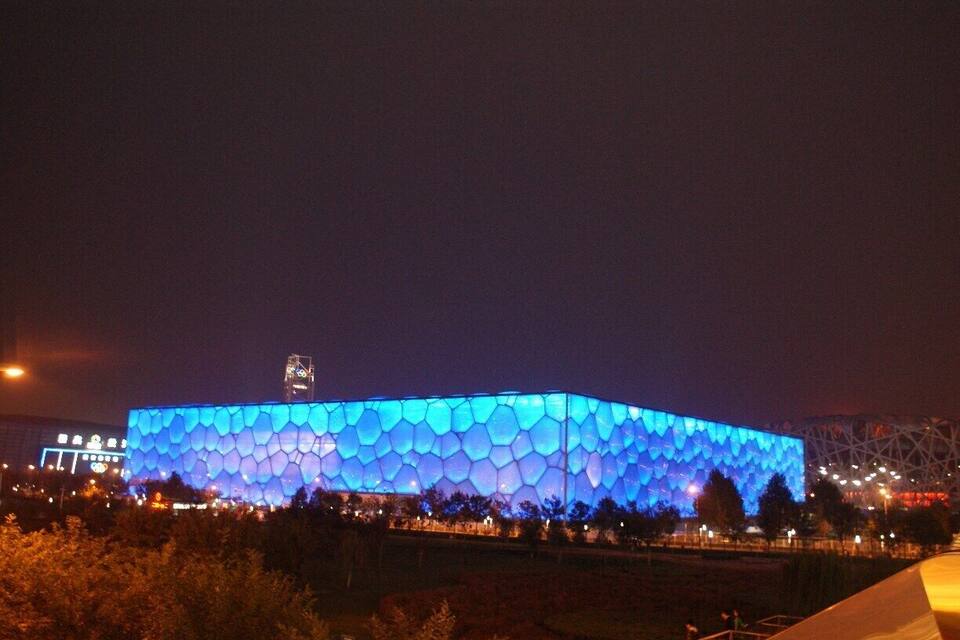 A large stadium with a distinctive honeycomb pattern of lights at night.