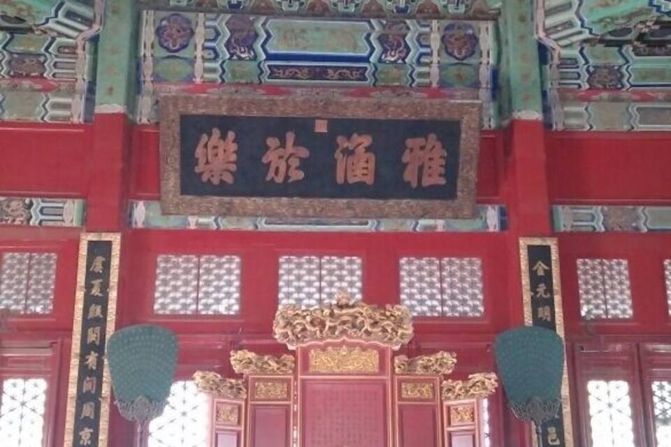 A traditional Chinese temple interior with ornate decorations, a large altar, and a sign with Chinese characters.