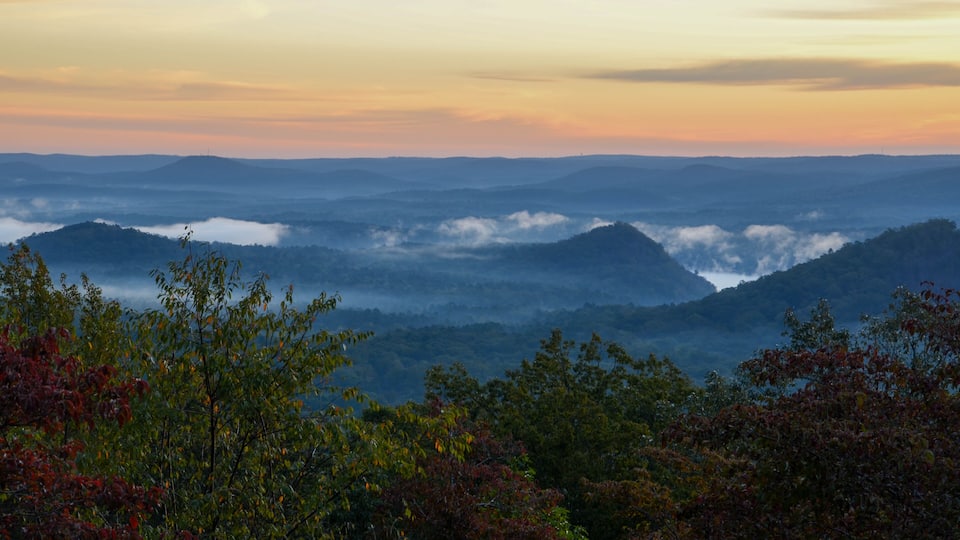 A mountainous landscape with a view of the horizon and a layer of clouds below.