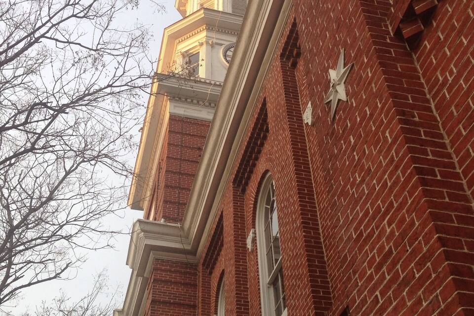 A red brick building with a clock tower and a weather vane.