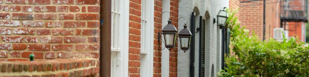 A brick building with white window frames and black wrought iron railings.