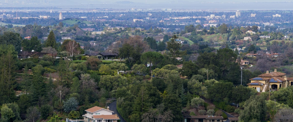 A cityscape with dense residential areas, green spaces, and distant city skyline.
