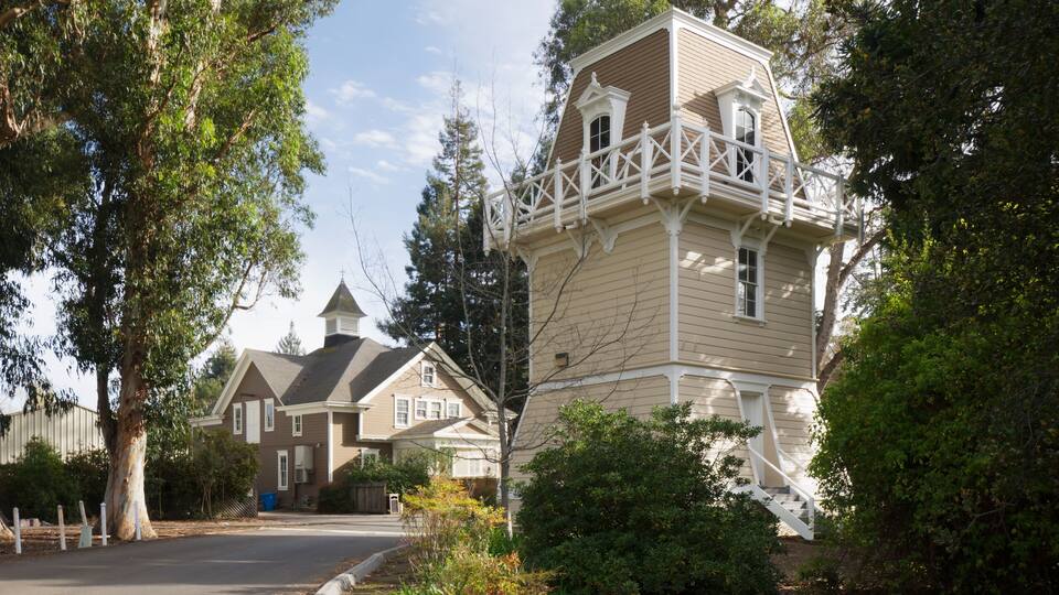 A two-story house with a balcony and a tower-like structure.