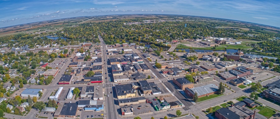 An aerial view of a town with a river, industrial buildings, and a large open field.