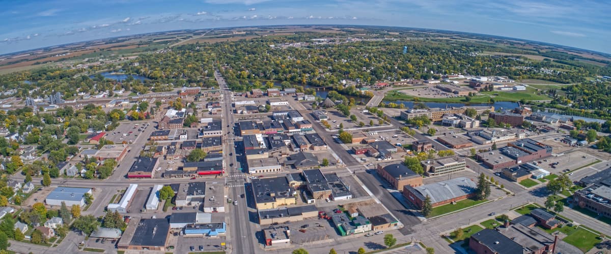 An aerial view of a town with a river, industrial buildings, and a large open field.