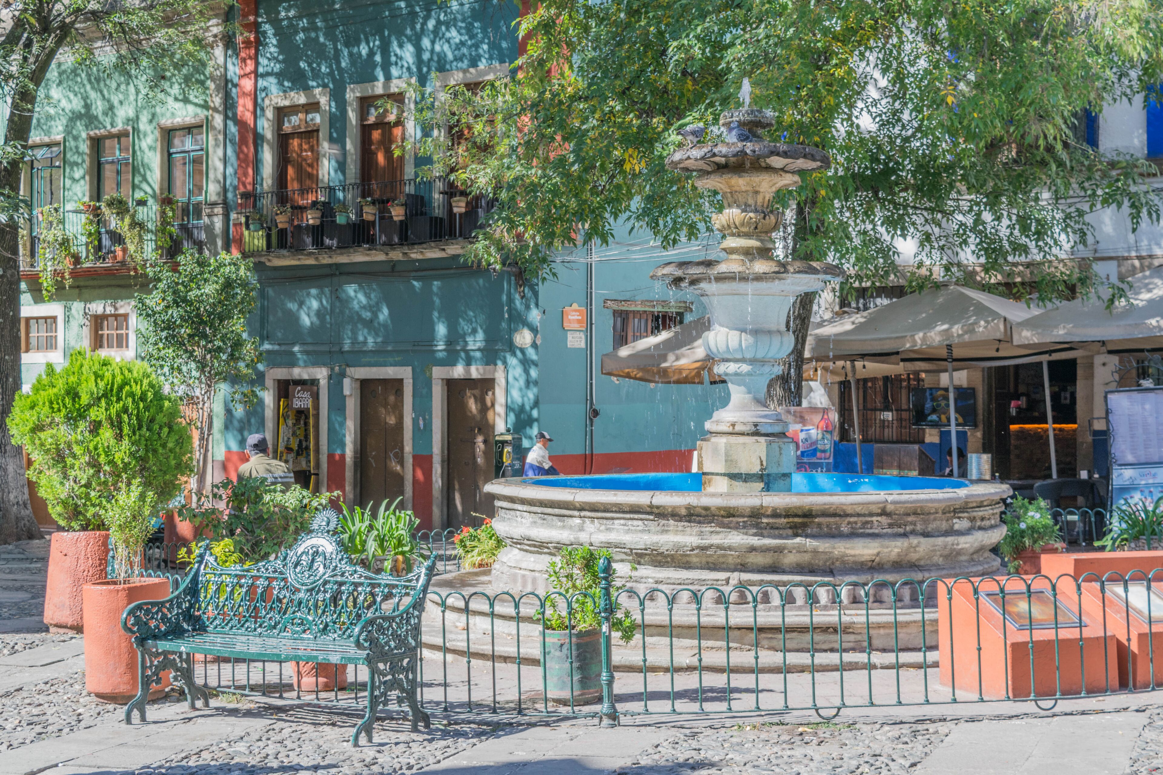 Una fuente en una plaza rodeada de edificios y árboles.