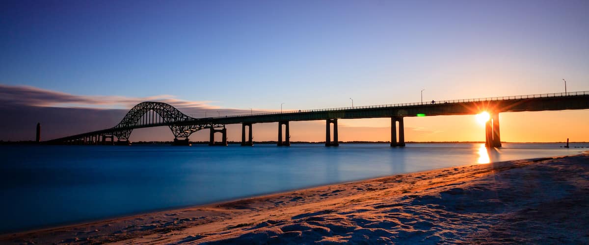 A bridge over calm water at sunset.