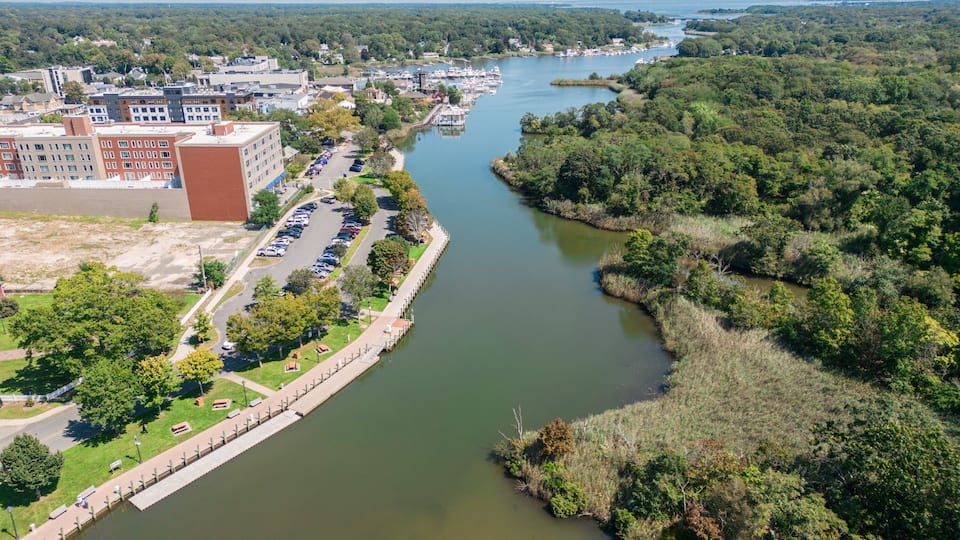 A river with a bridge, a parking lot, and buildings.