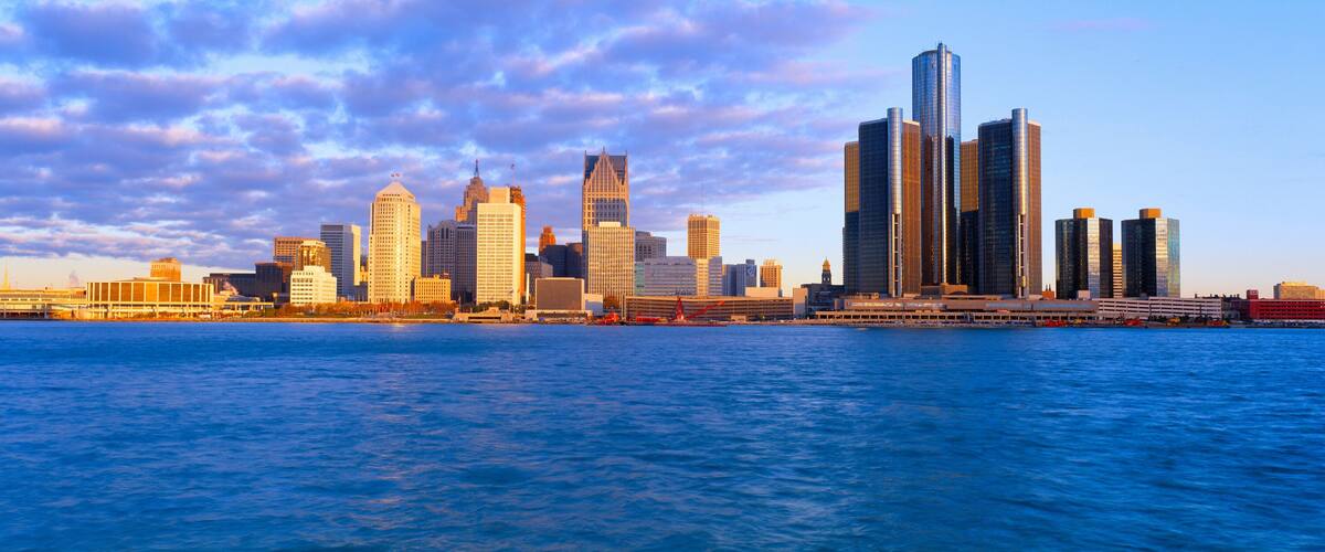 A city skyline with prominent skyscrapers and a body of water in the foreground.