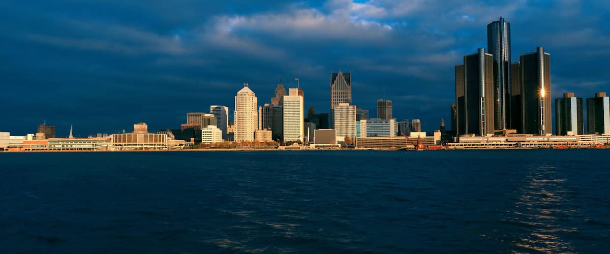 A city skyline with a variety of high-rise buildings, including a distinctive skyscraper with a pointed top, and a waterfront in the foreground.