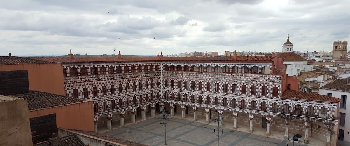 A courtyard with tiled roofs and a large building with a patterned facade.