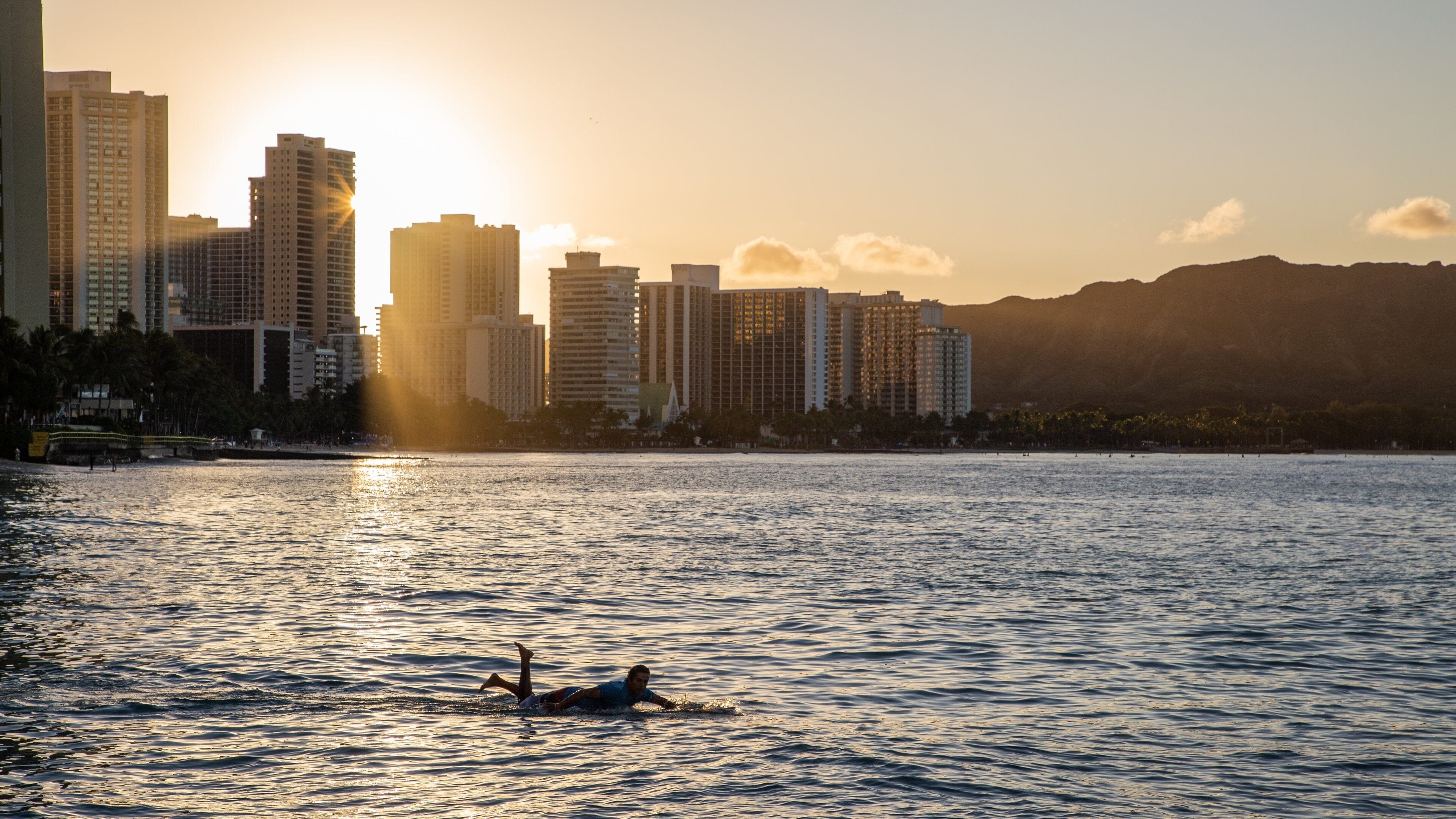 Waikiki Beach which includes surfing, a sunset and a coastal town
