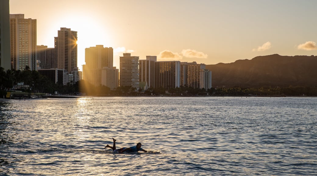 Waikiki Beach which includes surfing, a sunset and a coastal town