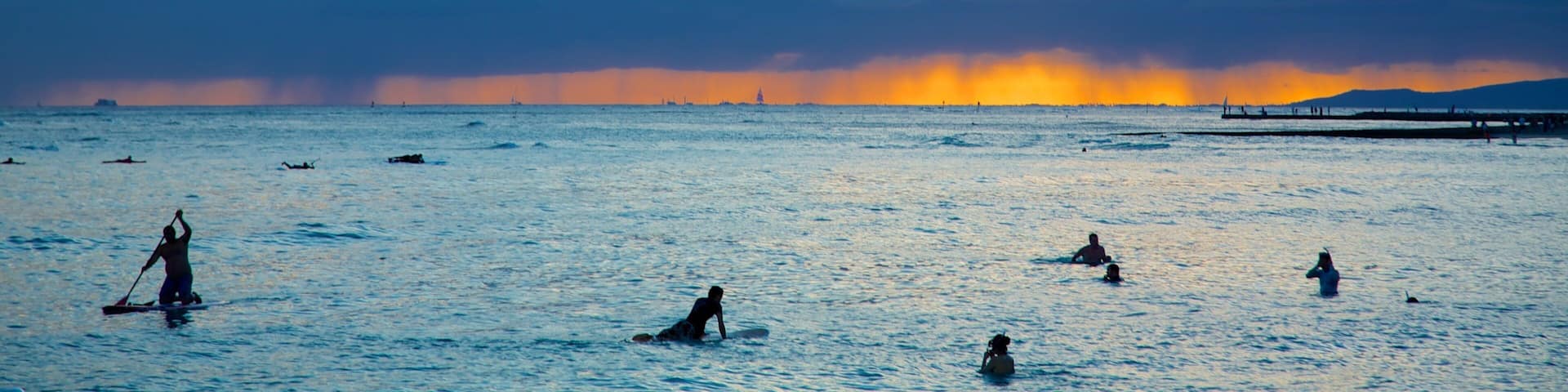 Waikiki Beach showing general coastal views, surfing and a sunset