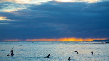 Waikiki Beach showing general coastal views, surfing and a sunset