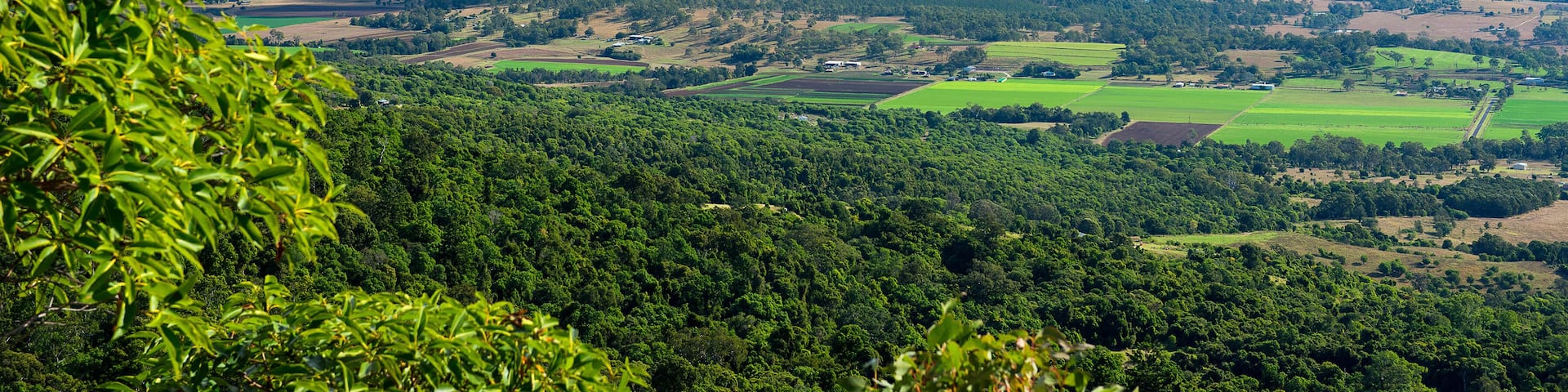 A mountainous landscape with a valley, green fields, and scattered buildings.